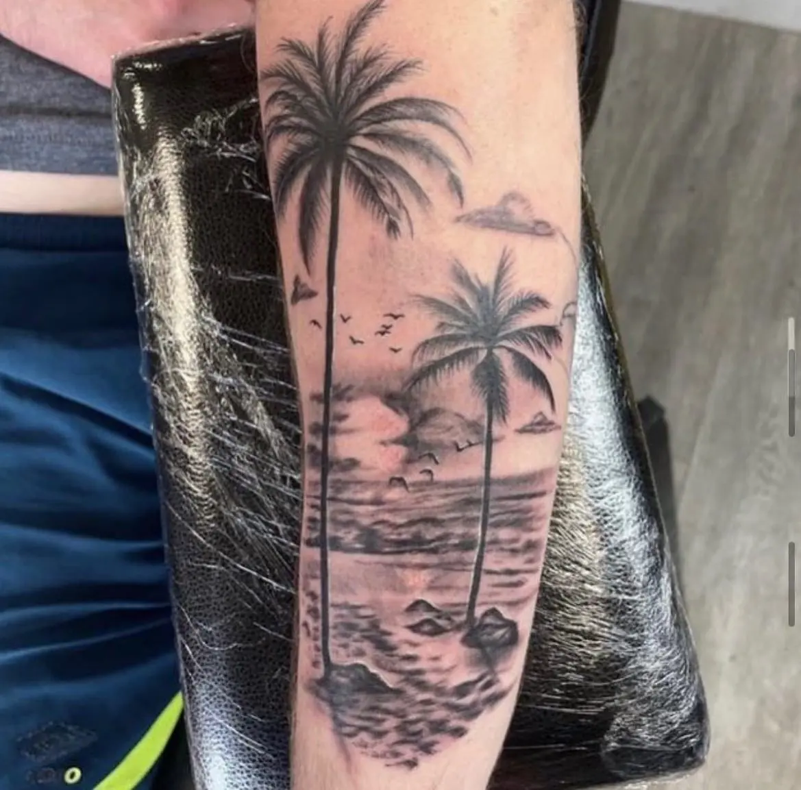 Paysage de plage tatoué en noir et gris sur l'avant-bras